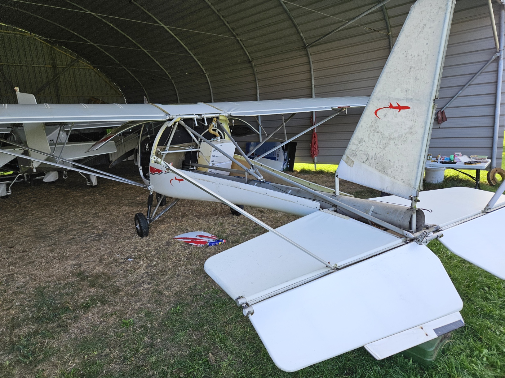 An Ikarus C42 3-axis microlight in a hanger. The top rear fuselage removed exposing the main strut and all the mechanics for the tail plane.